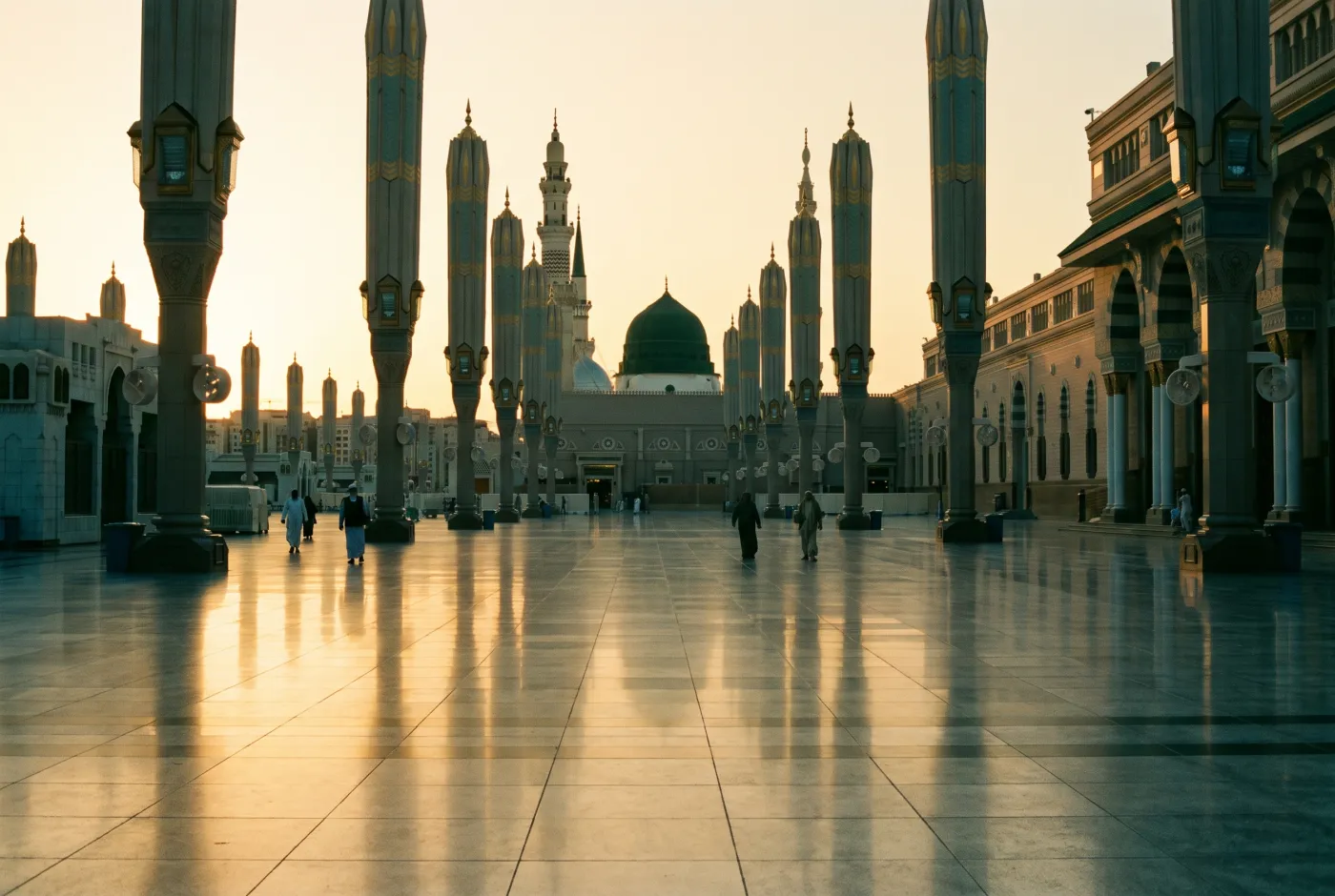 The courtyard of Al-Masjid an-Nabawi at first light, umbrellas folded above pale marble